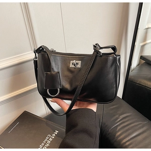 Detail of minimalist black shoulder bag with silver turn-lock and metallic ring hardware