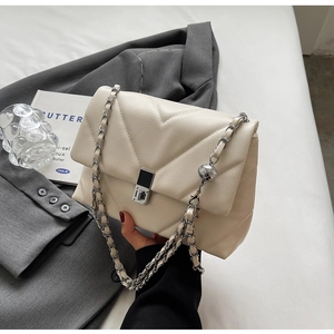 Close-up of V-shaped quilted cream leather shoulder bag with silver chain and metal lock