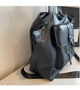 Détail d'un sac cabas en cuir noir avec bandoulière en nylon réglable et crochets argentés
