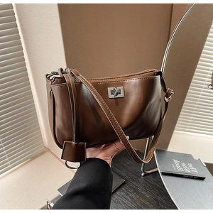 Detail of vintage brown leather underarm bag featuring a silver twist-lock metal buckle