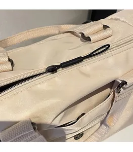 Detail of smooth metal zipper and black cord puller on white nylon tote bag