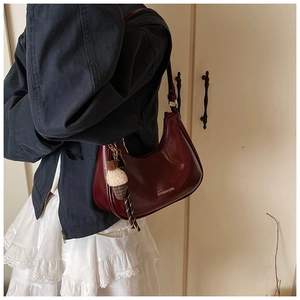 Détail du sac demi-lune en cuir verni bordeaux avec breloque glace et logo