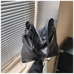 Detail of black faux leather tote bag with silver square buckle in a lifestyle setting