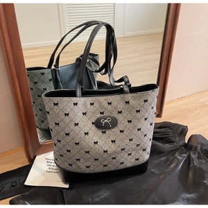 Détail du sac cabas gris en jacquard avec motifs nœuds et anses en cuir noir