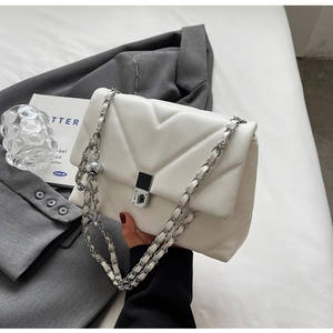 Close-up of white quilted leather crossbody bag with silver chain strap and metal lock