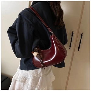 Détail du sac sous le bras demi-lune bordeaux avec charm en peluche et logo chic