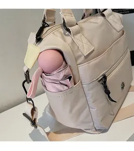 Detail of off-white nylon tote bag showing functional side pocket with a pink umbrella