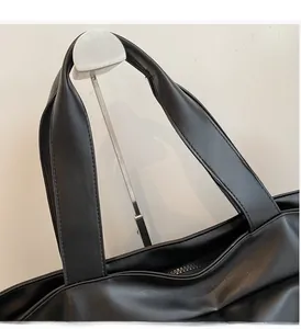 Détail de la poignée large renforcée avec coutures soignées et zip en métal du sac noir