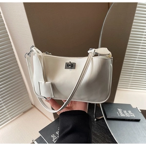 Close-up of white minimalist shoulder bag featuring a silver metal twist-lock buckle