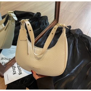Detailed close-up of cream woven texture hobo bag with metallic strap buckles