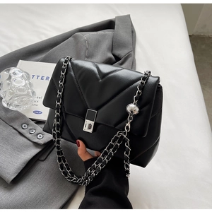 Detail of black quilted leather shoulder bag with silver chain and sphere charm