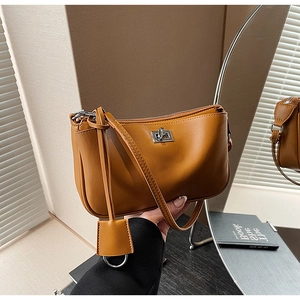 Close-up of caramel crescent shoulder bag featuring silver metal twist lock and leather charm