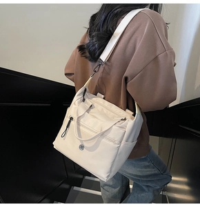 Detail view of cream nylon tote bag with multi-pocket design and adjustable strap