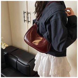 Détail du sac croissant bordeaux avec logo doré et bandoulière ajustable