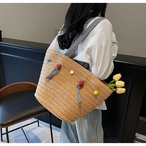 Détail du sac cabas en paille tissée avec perles colorées et bandoulière rayée pour la plage