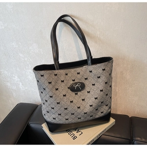 Détail du sac en tissu gris avec motifs nœuds noirs et emblème logo argenté