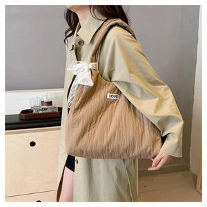 Dettaglio borsa shopper marrone con texture a pieghe verticali e fiocco in pizzo bianco