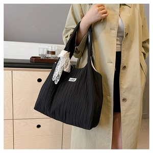 Dettaglio di una borsa tote nera plissettata con toppa LOVE bianca e nastro di pizzo