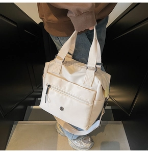 Detail of cream tote bag with hidden front pocket and adjustable shoulder strap