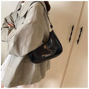 Détail d'un sac hobo noir avec logo imprimé et texture en cuir synthétique brillant