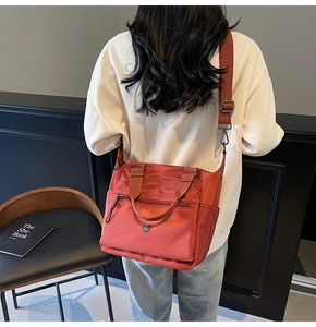 Detail of red water-resistant nylon tote bag with multi-zipper pockets and wide strap