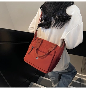 Detail of orange nylon tote bag with front zipper pocket and adjustable strap