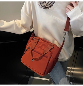 Detail view of caramel red nylon tote with multi-zipper pockets and adjustable strap