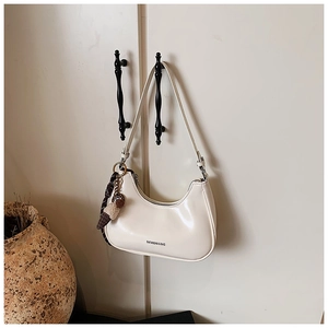 Détail du sac hobo blanc brillant avec breloque pompon à carreaux sur une poignée
