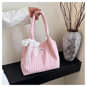 Dettaglio della borsa rosa con etichetta LOVE, fiocco in pizzo bianco e trama a pieghe