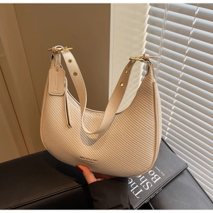Macro detail of beige woven hobo bag with gold hardware and brand tag on a neutral setting