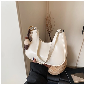 Détail du sac croissant blanc crème avec breloque en peluche et logo de la marque