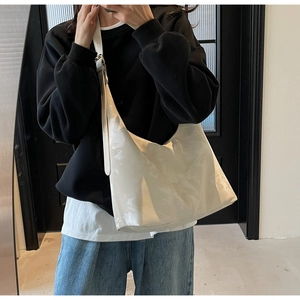 Detailed view of large white hobo bag with adjustable strap worn by a female model