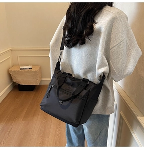 Close-up of black multi-pocket canvas tote bag with adjustable shoulder strap