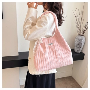 Dettaglio della borsa tote rosa a pieghe con pizzo bianco e toppa con scritta LOVE
