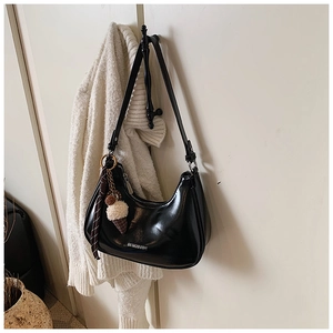 Détail du sac croissant en cuir verni noir avec pendentif peluche et ruban à carreaux