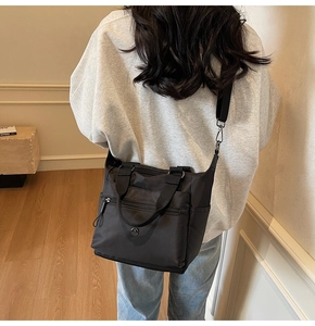 Rear view of a model wearing the black nylon multi-pocket tote bag in a cozy home setting