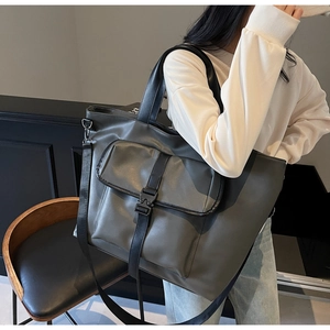 Détail d'un grand sac cabas gris avec bandoulière réglable et boucle tactique mat