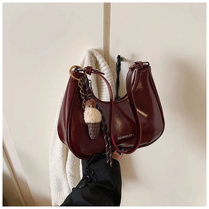 Détail du sac croissant bordeaux brillant avec charm en peluche et fermeture éclair en métal