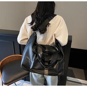 Vue mannequin montrant la taille d'un grand sac cabas en cuir noir avec large bandoulière