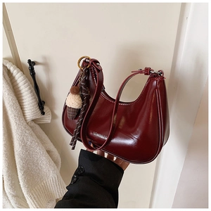 Détail du sac sous le bras rouge foncé avec pendentif crème glacée et logo argent