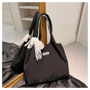 Dettaglio della borsa tote nera trapuntata con fiocco di pizzo bianco e toppa LOVE