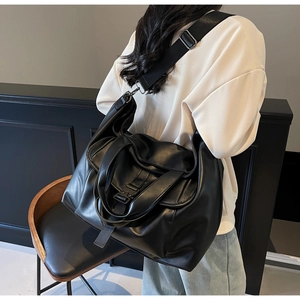 Gros plan d'un grand sac cabas noir rétro avec bandoulière large en tissu et cuir mat