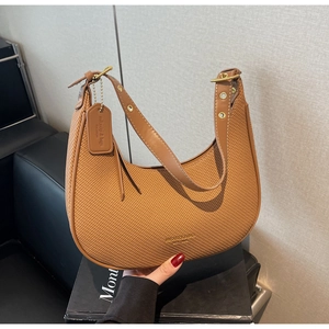 Detail of a brown woven hobo bag showing the crescent shape and gold buckle hardware