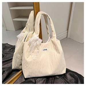 Dettaglio di una borsa tote trapuntata bianco crema con fiocco in pizzo e toppa LOVE