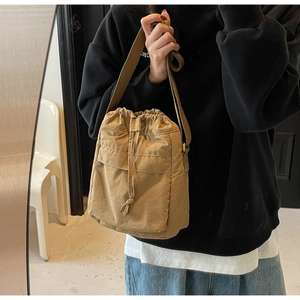 Dettaglio della borsa a secchiello kaki con coulisse e tracolla regolabile sulla modella