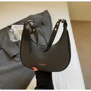 Detail of black woven hobo bag showing gold logo and premium metal hardware accents