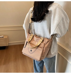 Detail of apricot nylon tote bag with multi-zipper pockets and adjustable wide strap