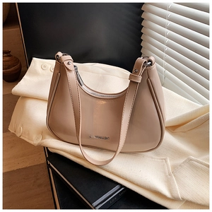 Détail du sac croissant abricot avec logo argenté sur chemise en lin beige et ombres