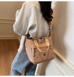 Detail of nylon tote bag showing adjustable shoulder strap and metal logo in dusty rose