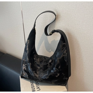 Close-up of black tie-dye hobo bag with adjustable strap and gold metal buckle detail